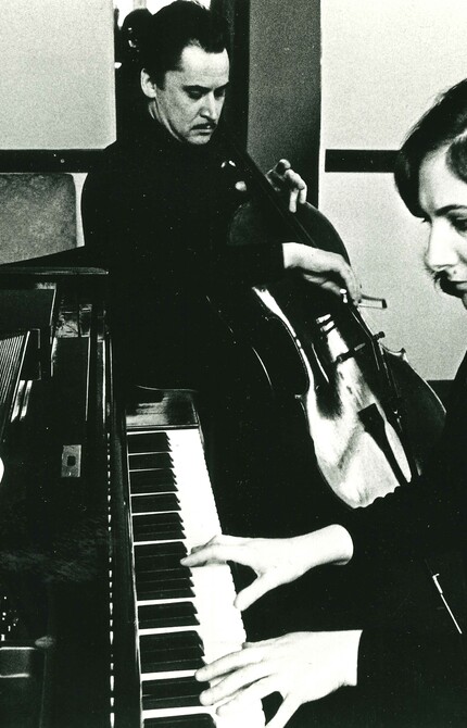 Marietta Orlov playing piano in the foreground, with a cellist in the background