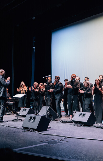 Choir wearing all black, performing passionately on stage