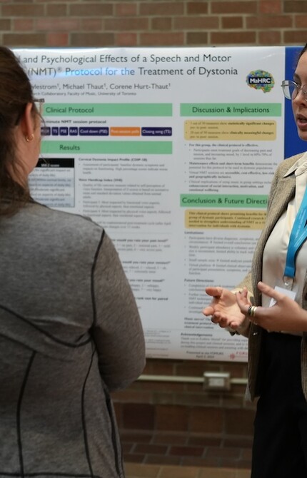 Two people giving a presentation to one person, with an information board in the background.