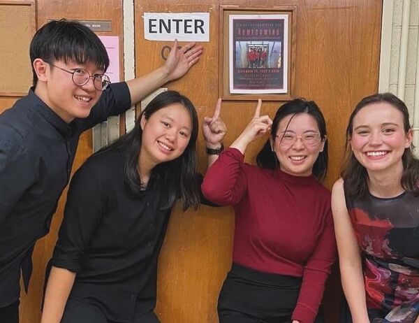 Group standing in front of a door, pointing at a poster, with expressions of excitement and engagement.