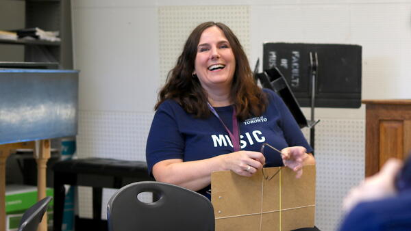 Thumbnail Image for Staff member smiling in a classroom holding a clipboard.