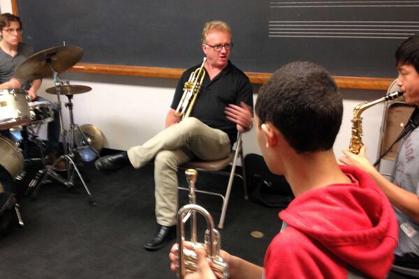 Thumbnail Image for Jim Lewis holding trumpet and coaching student on saxophone.