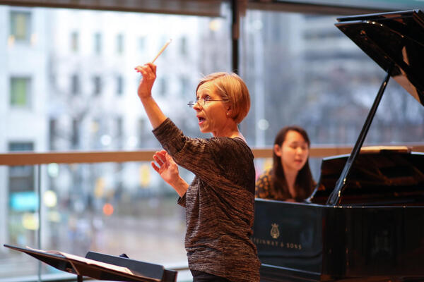 Thumbnail Image for Sandra Horst conducting with a pianist in the background