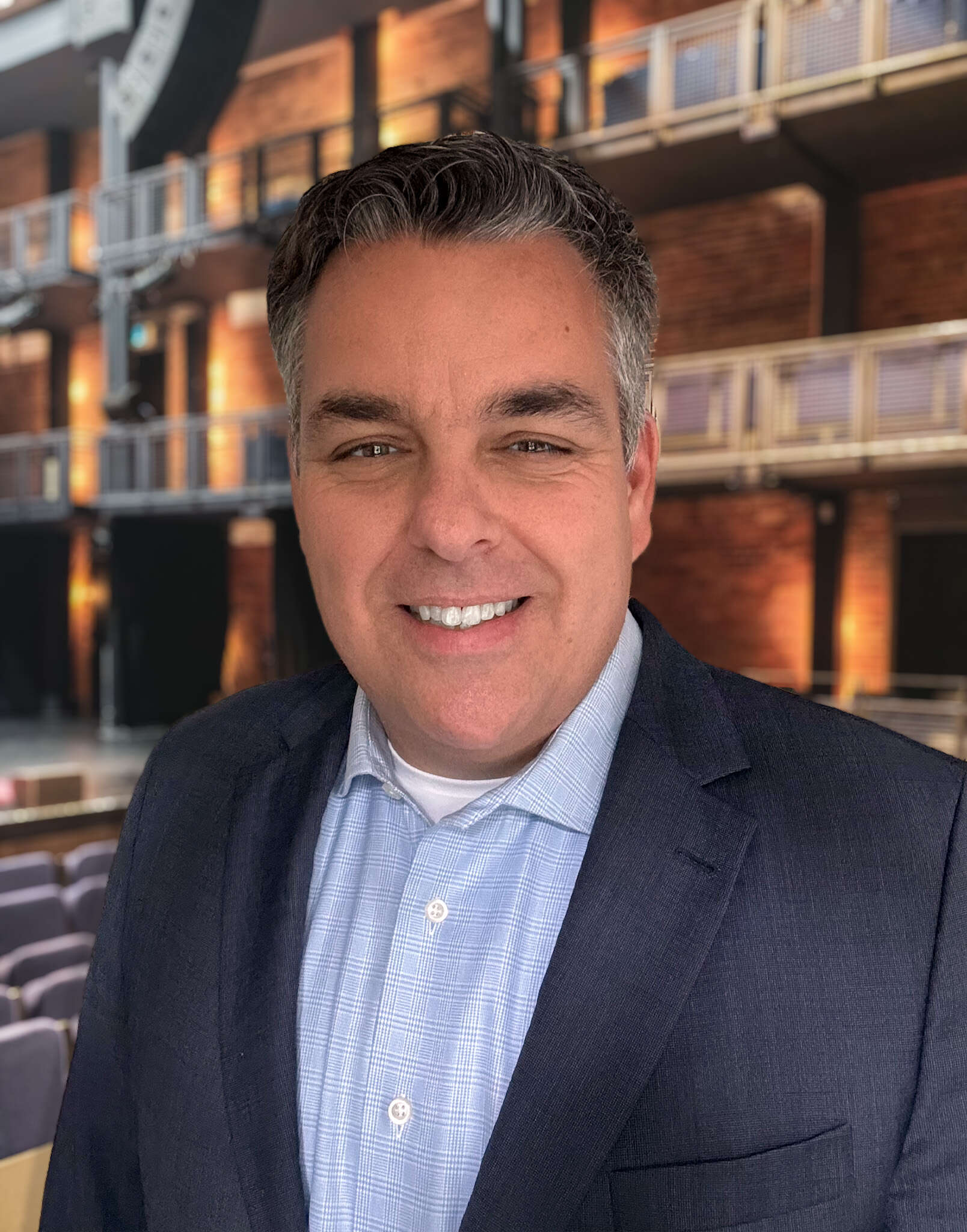 Person smiling standing in an auditorium with balconies in the backdrop