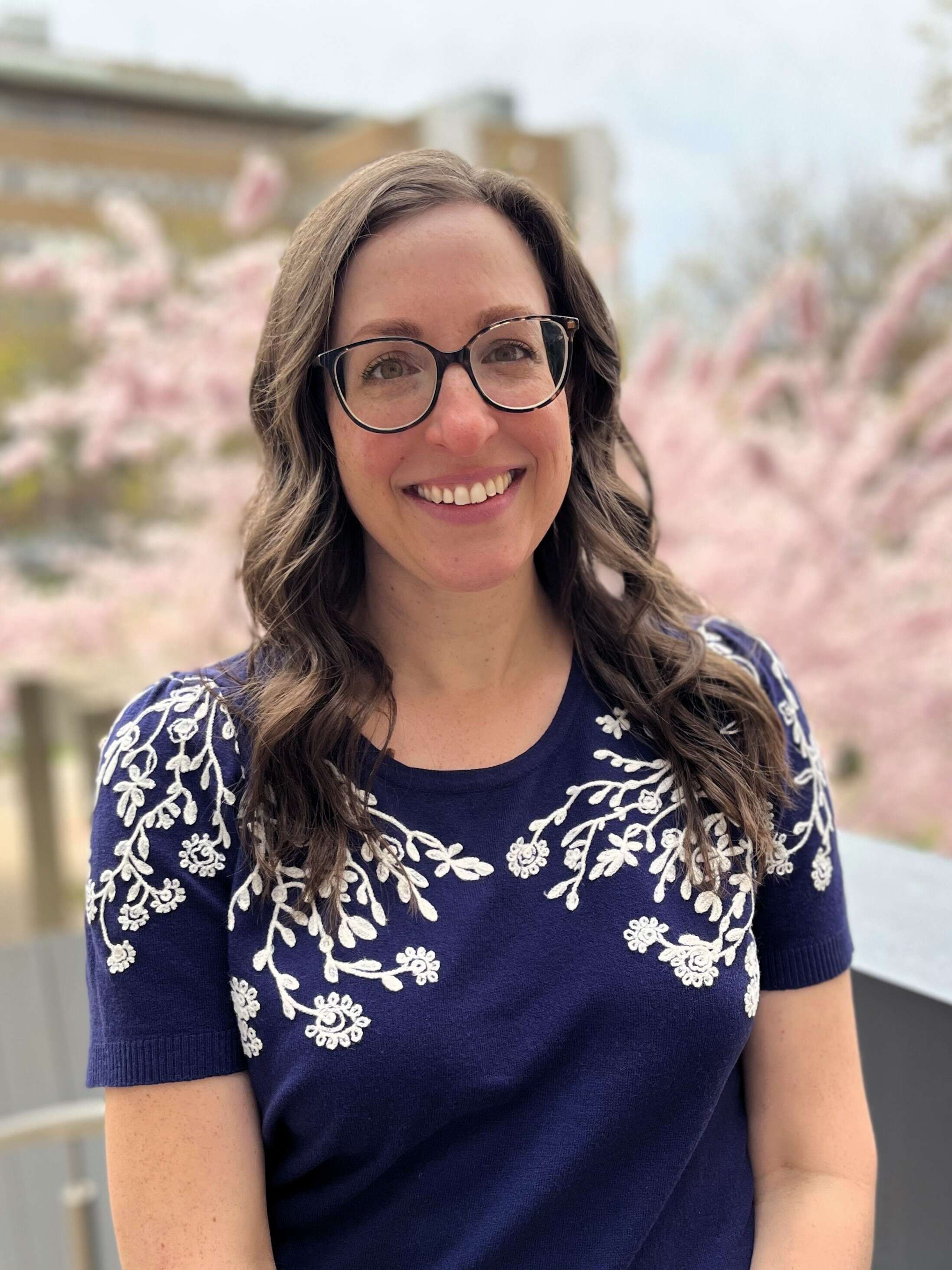 Headshot of Calista Biermans Tunney in front of cherry trees in blossom.