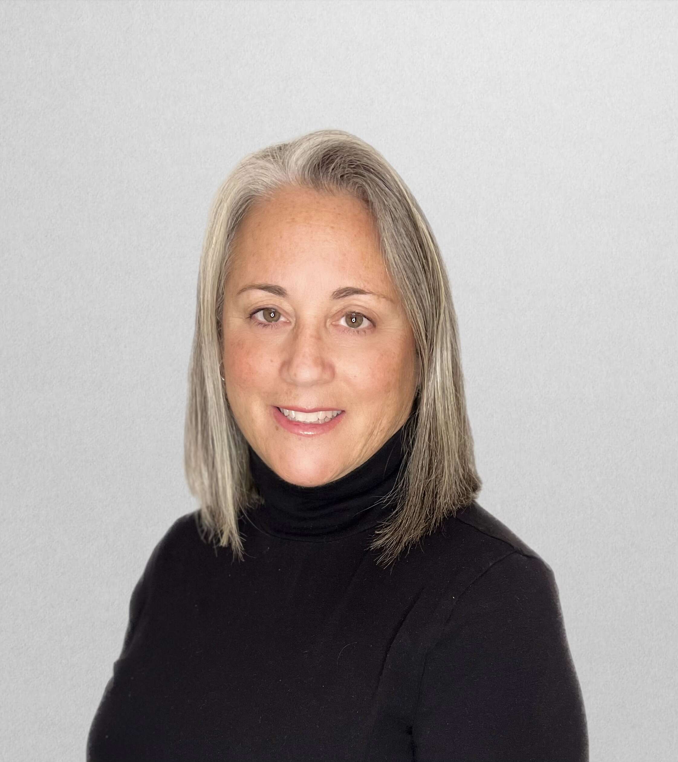 Woman wearing a black shirt, smiling at the camera, with a white background.