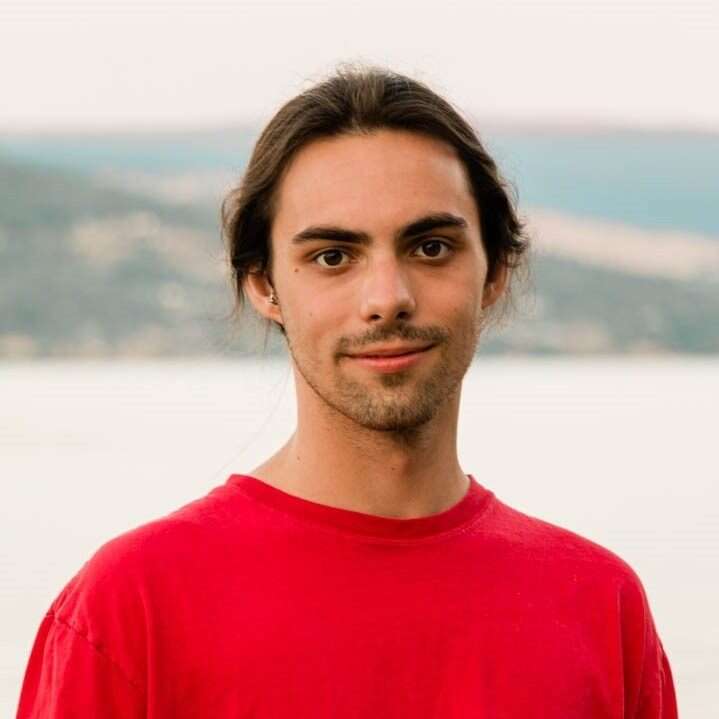 Young person wearing a red t-shirt standing in front of a lake