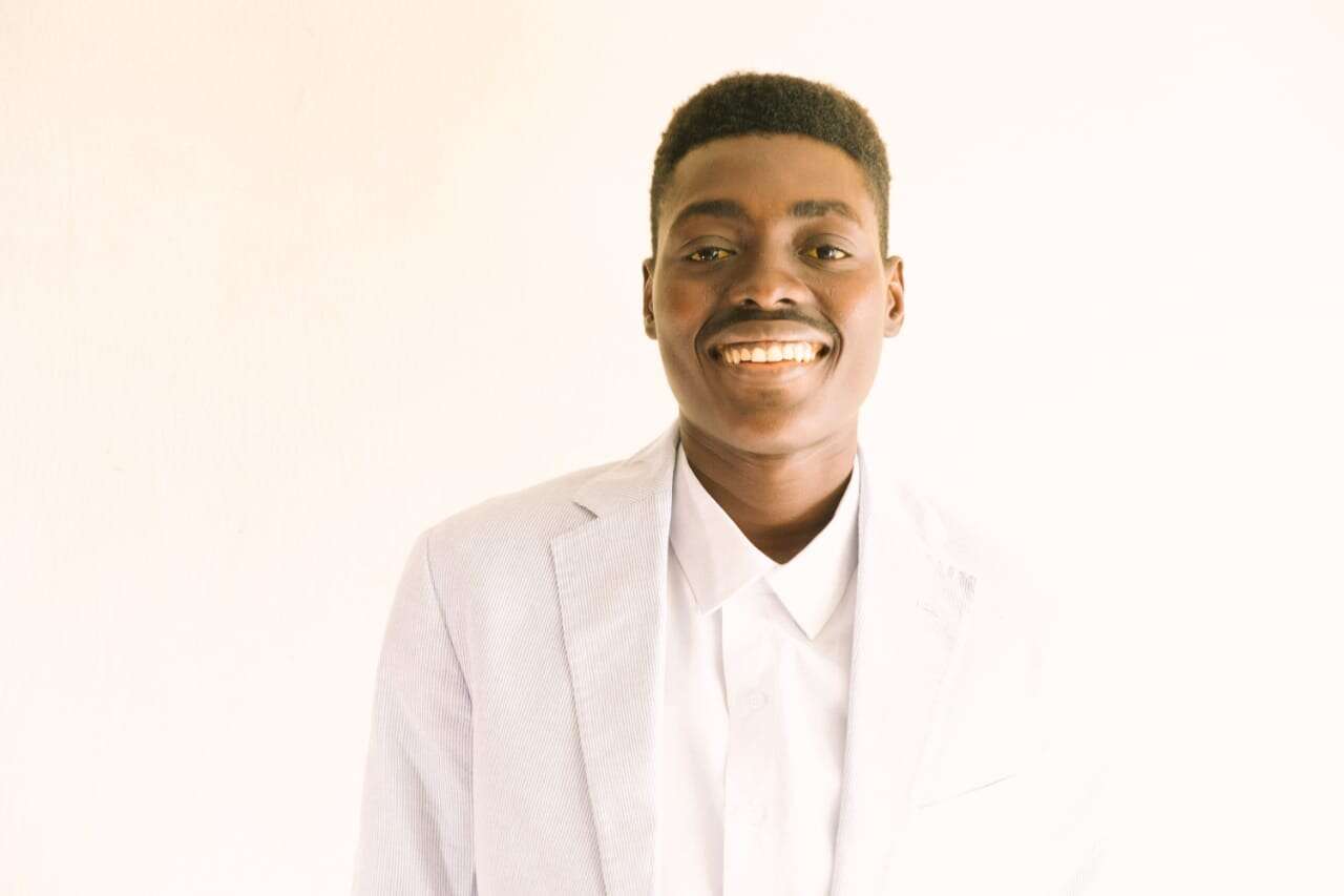 Person smiling wearing all white, in front of a white background