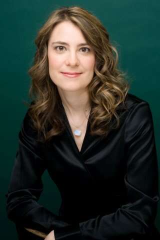 Headshot of a person smiling, wearing a black satin shirt, with a green background that adds vibrancy.