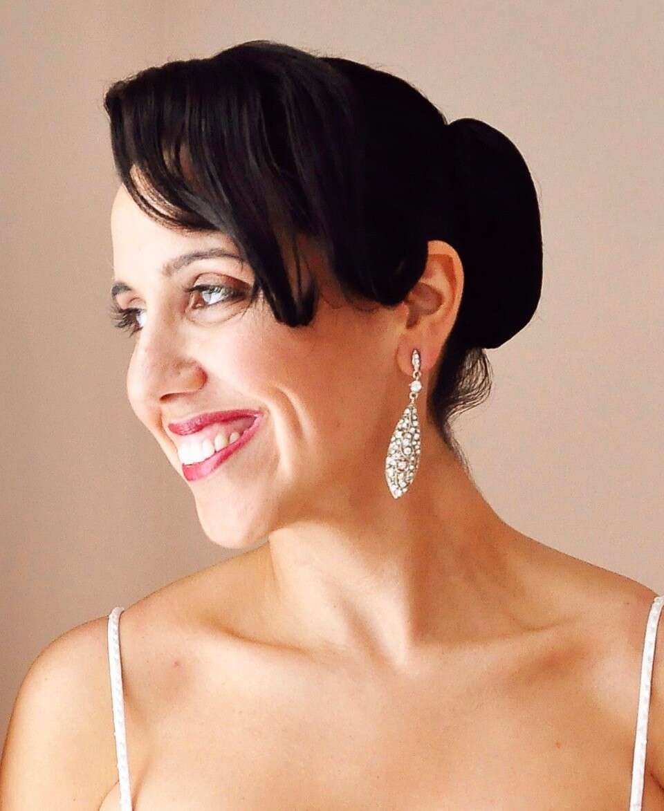 Headshot of a person with their hair in a low bun, smiling and looking off to the side.