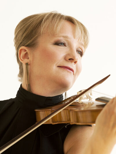 Professional portrait of Patricia Ahern looking to the side and playing her violin against a white backdrop.