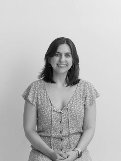 Black and white portrait of Kristen Antunes sitting down and smiling