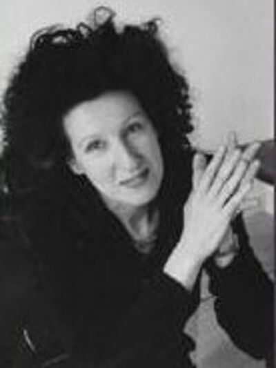 Black and white photo of a person with big hair, wearing a black shirt, holding their hands in a praying position