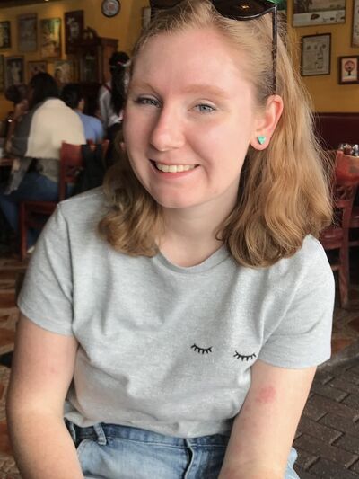 Person with shoulder length hair smiling in a coffee shop