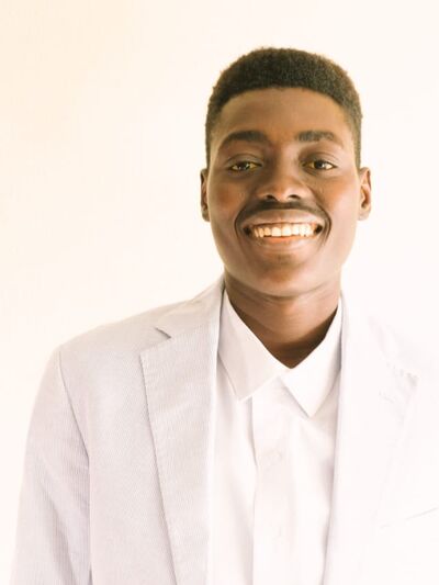 Person smiling wearing all white, in front of a white background 