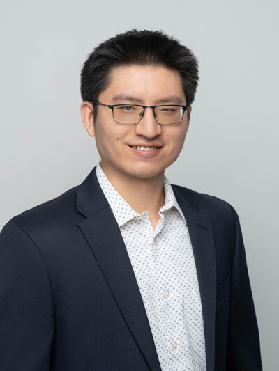 Man wearing glasses and a blazer in front of a white background
