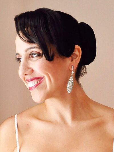 Headshot of a person with their hair in a low bun, smiling and looking off to the side.