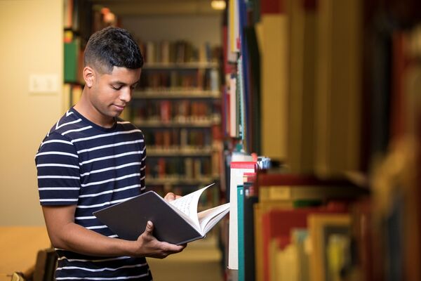 Student looking through score in music library stacks.