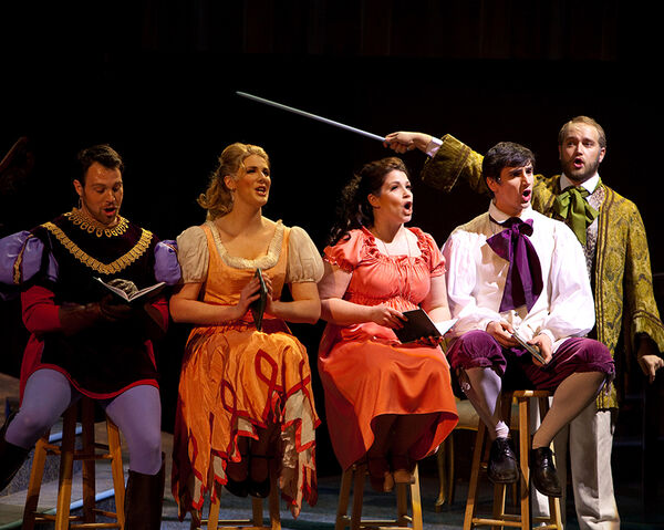 Five characters in a musical, singing and wearing colorful costumes.