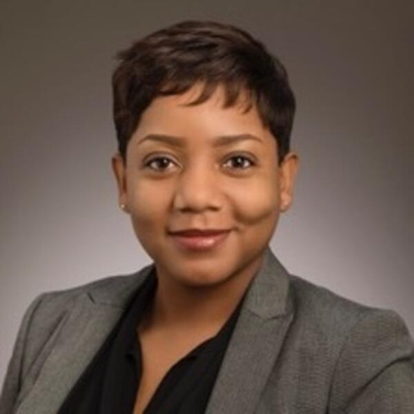 Portrait photo of person in a blazer in front of a grey backdrop
